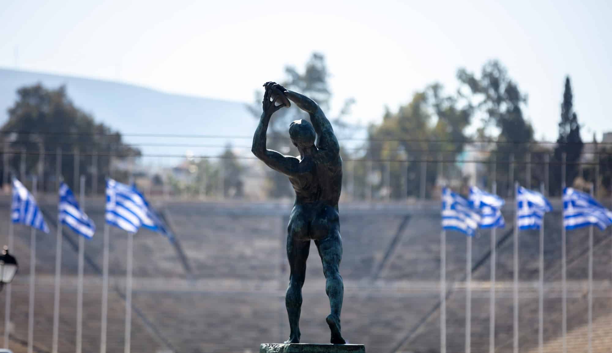 Athens, Greece. Discus thrower bronze statue, rear view. Panathenaic Stadium blur background