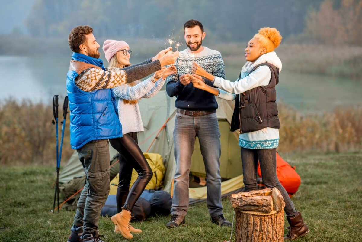 Friends in sweaters celebrating at the camping