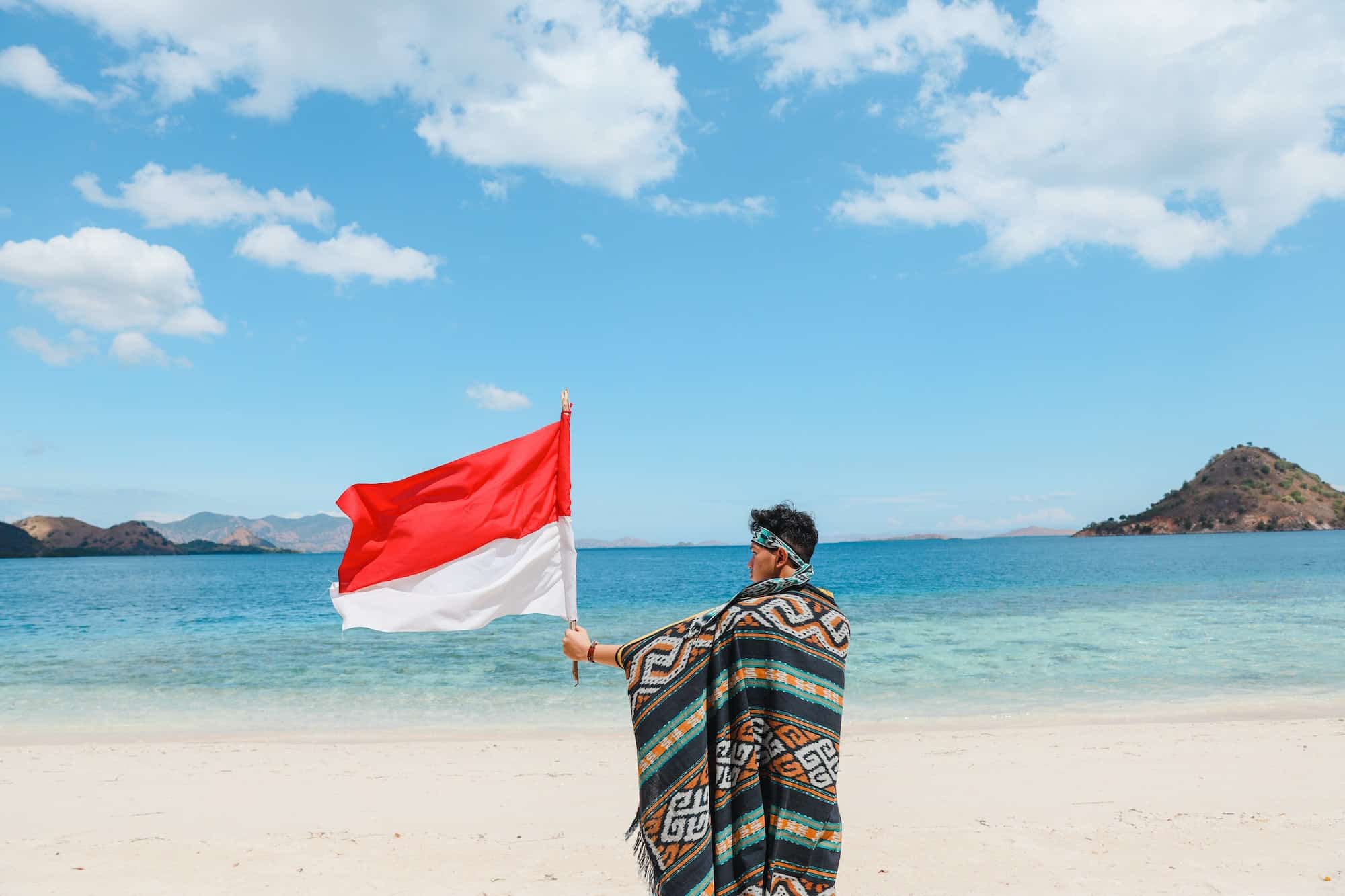 Indonesian native tribe man waving Indonesian flag on the beach