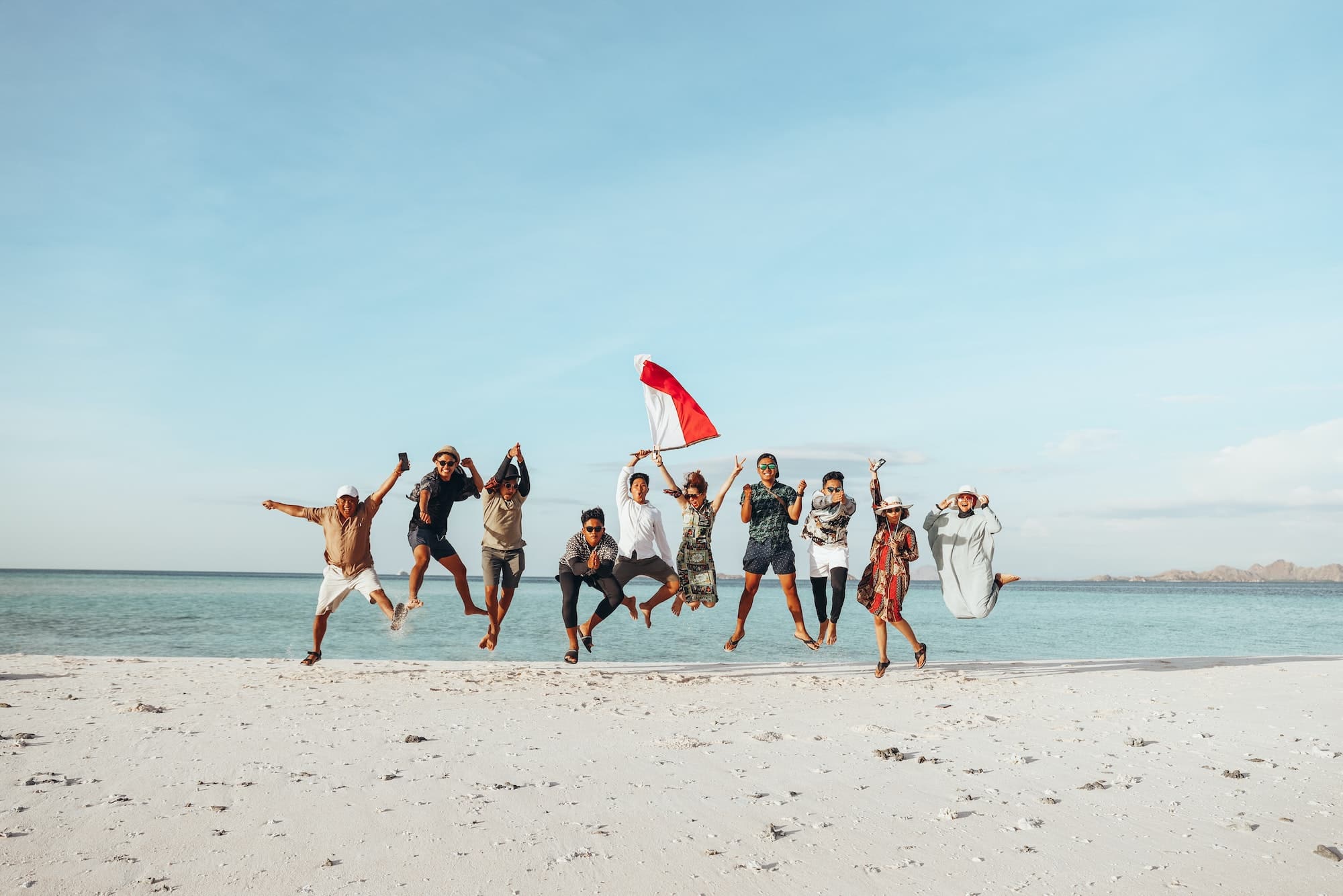 Indonesian people jumping together on the beach