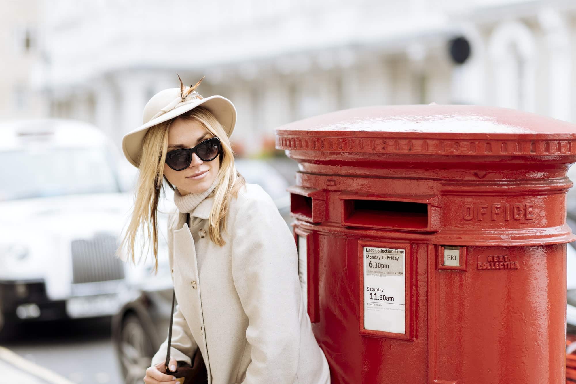 Stylish young woman waiting by red post box, London, England, UK