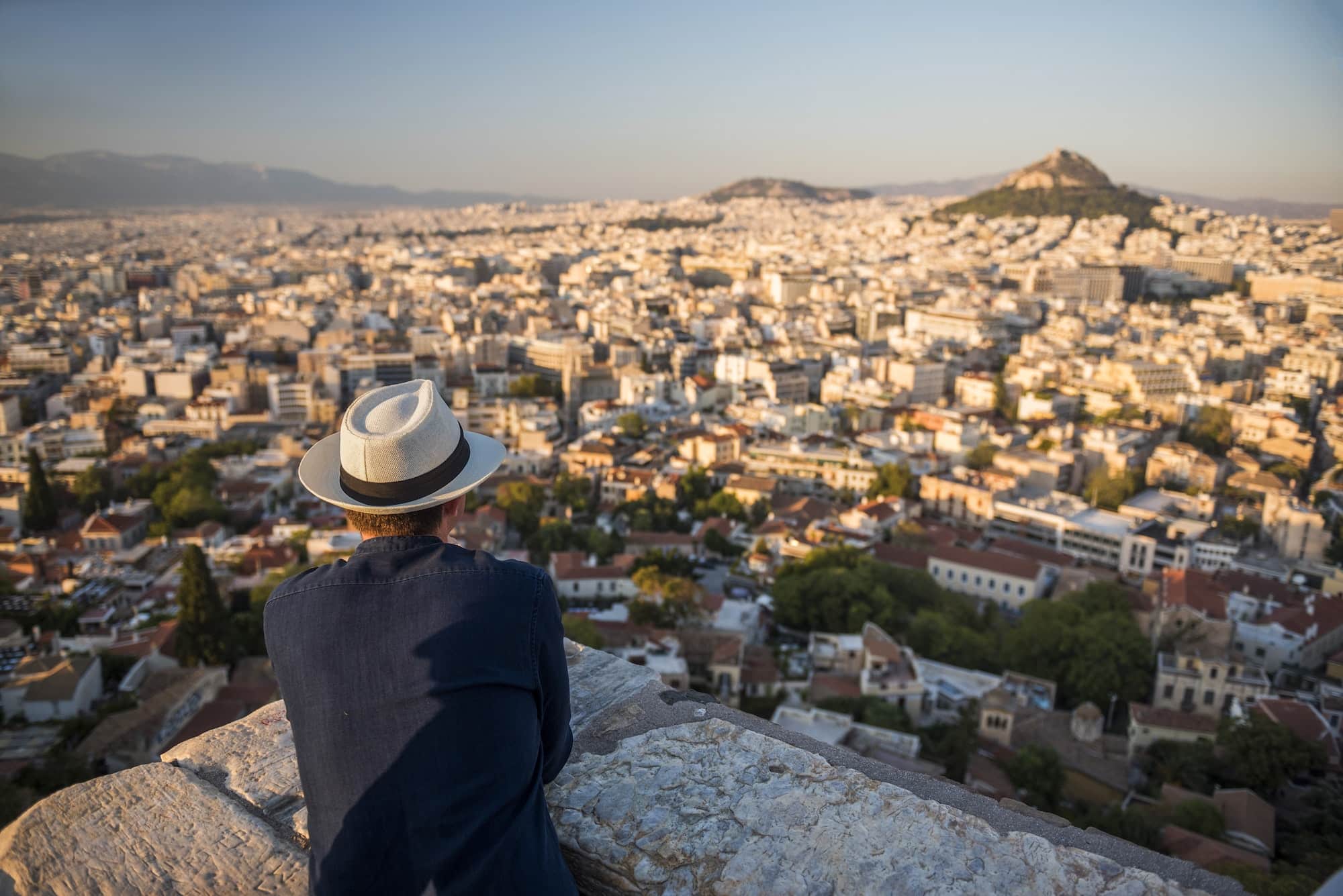Tourist man looking at view over Athens from Likavitos Hill on summer holiday, at The Acropolis, Att