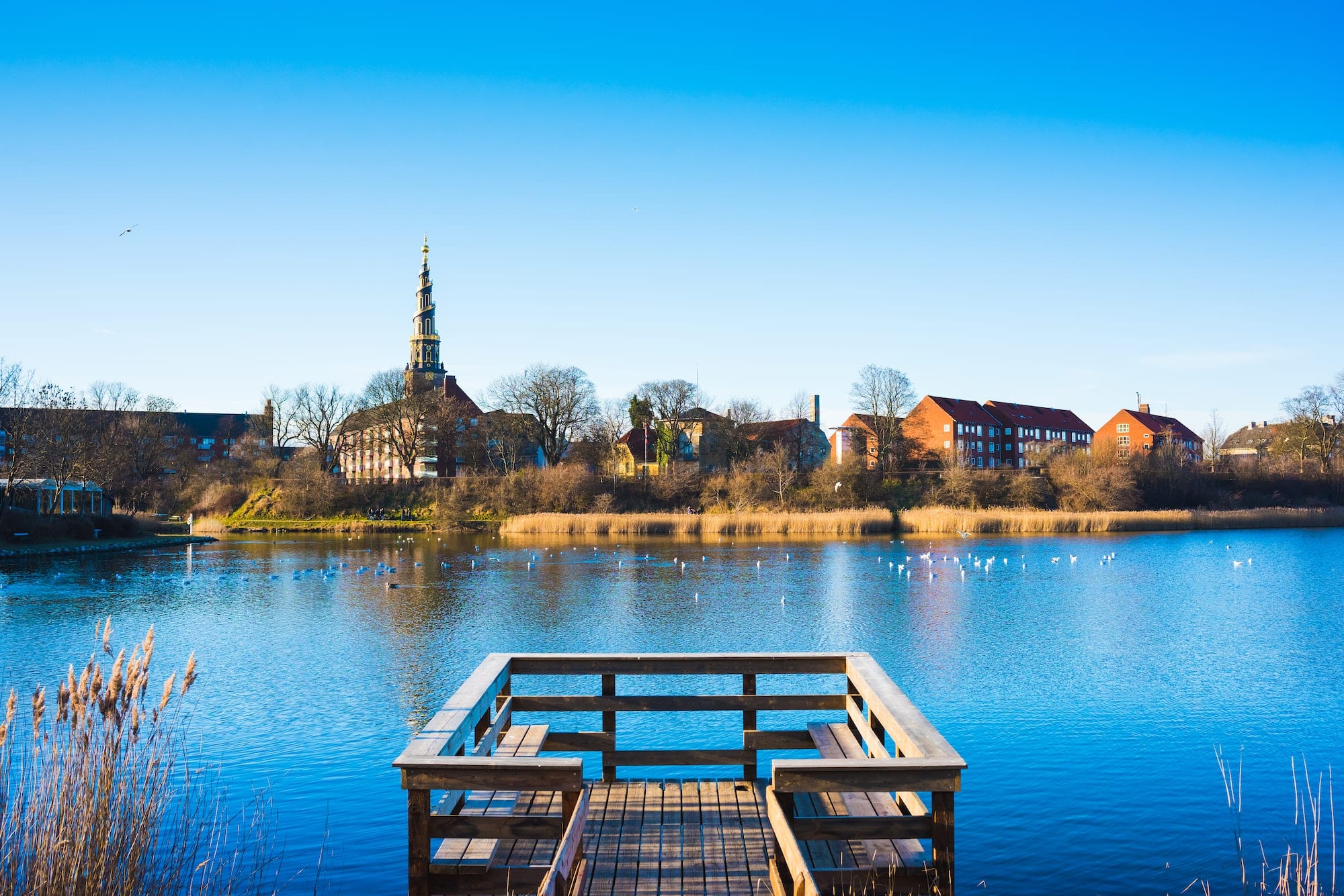 View of wooden pier on river and distant church spire, Copenhagen, Denmark