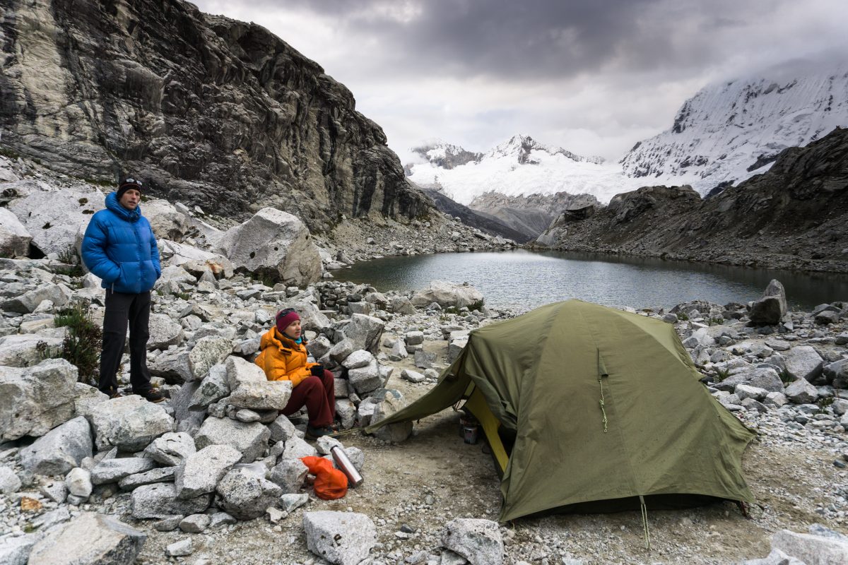 male and female mountain climber couple at a remote base camp in the Cordillera Blanca in Peru next to a small mountain lake
